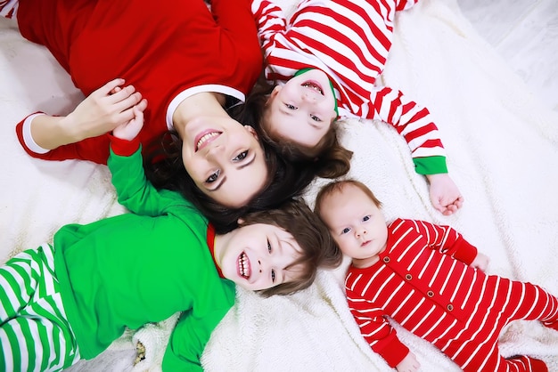 Una famiglia in pigiama a righe riposa a casa. I bambini vestiti da elfi sono sdraiati sul divano. Una famiglia felice.