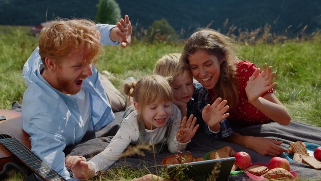 Una famiglia si siede sull'erba e gioca con un tablet.