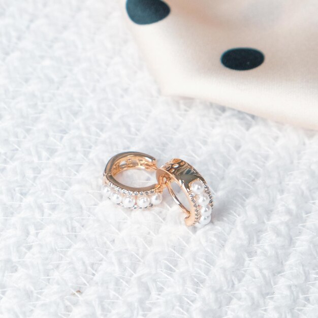 Una fede nuziale in oro adagiata su una superficie bianca con sopra un anello di diamanti.