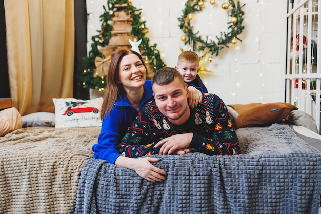 Una felice coppia familiare con un bambino nei luoghi di Capodanno L'atmosfera festosa di Capodanno nella cerchia familiare Decorazioni natalizie in camera da letto Decorazioni natalizie di Capodanno a casa