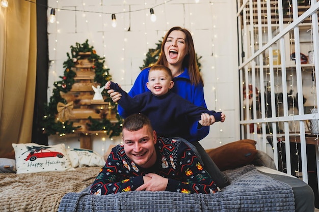 Una felice coppia familiare con un bambino nei luoghi di Capodanno L'atmosfera festosa di Capodanno nella cerchia familiare Decorazioni natalizie in camera da letto Decorazioni natalizie di Capodanno a casa