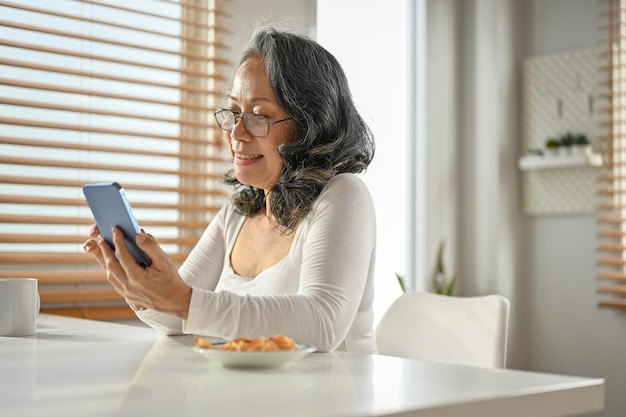 Una felice donna asiatica che usa il suo smartphone per chattare con qualcuno