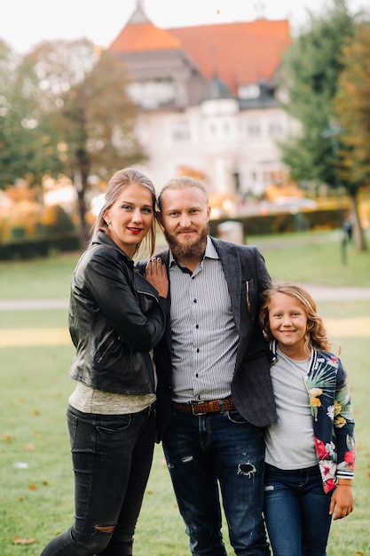 Una felice famiglia di tre persone corre tra i prati del centro storico austriaco