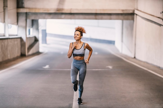 Una felice sportiva urbana corre in garage e si prepara per una maratona