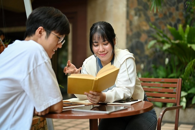 Una felice studentessa asiatica sta studiando e facendo i compiti con il suo amico maschio.