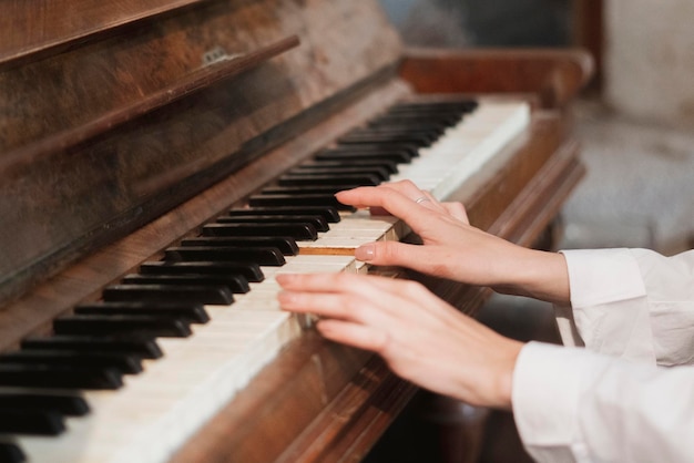 Una femmina passa a suonare il vecchio pianoforte vintage con tasti bianchi