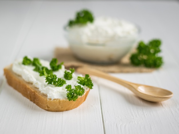 Una fetta di pane fresca spalmata di crema di ricotta con prezzemolo sul tavolo.