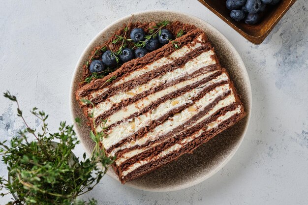 Una fetta di torta al cioccolato con miele e crema al burro. Torta al miele decorata con frutti di bosco freschi.