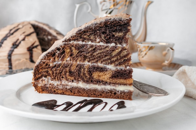 Una fetta di torta marmorizzata con crema Guarnita con glassa e cioccolato Su un piatto bianco con una forchetta Primo piano