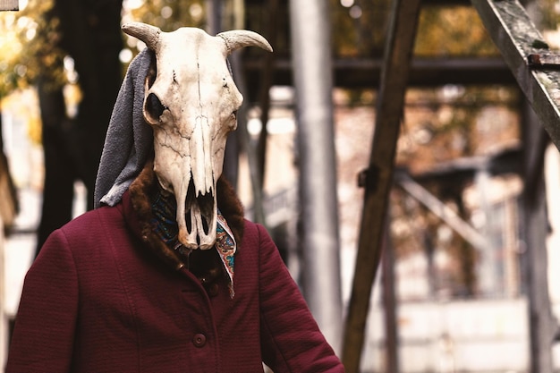 Una figura sinistra con il cappotto di una vecchia e con un teschio di animale al posto della testa