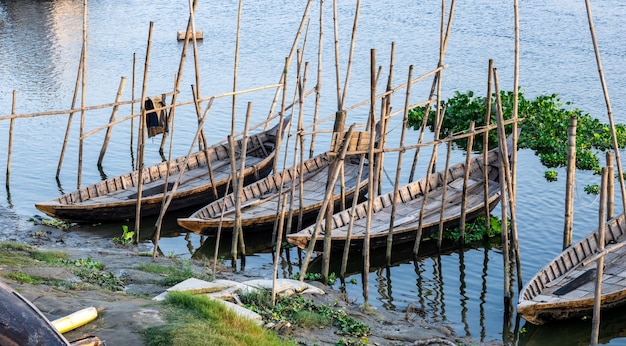 Una fila di barche passeggeri in legno parcheggiate sul fiume nel villaggio rurale