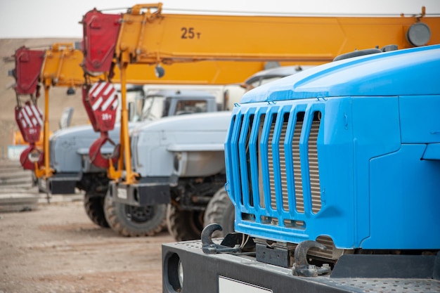 Una fila di grandi gru per autocarri e macchine in un cantiere edile industriale