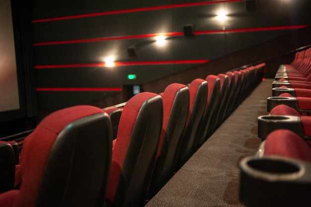 Una fila di sedie rosse in un teatro con luci rosse alle pareti.