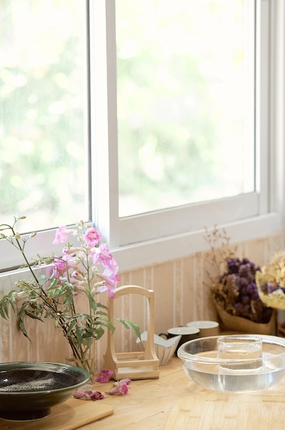 Una finestra con una cornice bianca e una pianta con dentro un fiore rosa.