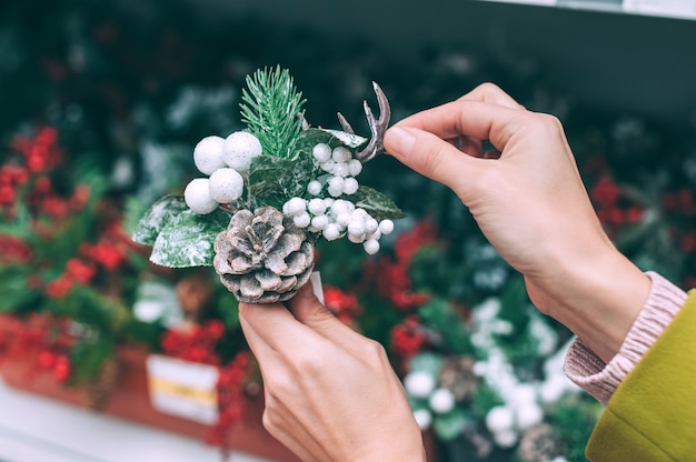 Una fioraia tiene in mano un ramo di abete con bacche e coni per la decorazione di Natale e Capodanno.