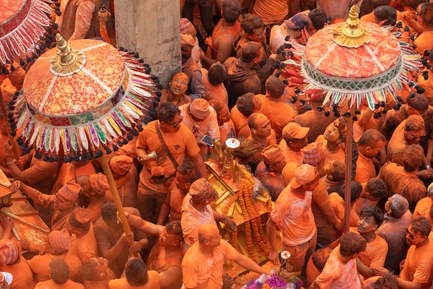 Una folla di persone è riunita in arancione e giallo con la parola "holi" in alto.