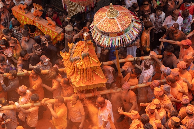Una folla di persone si è radunata attorno a una statua di un uomo con vernice arancione sulla schiena.