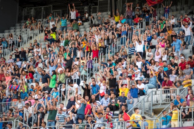 Una folla sfocata di spettatori in una tribuna di uno stadio durante una partita di calcio