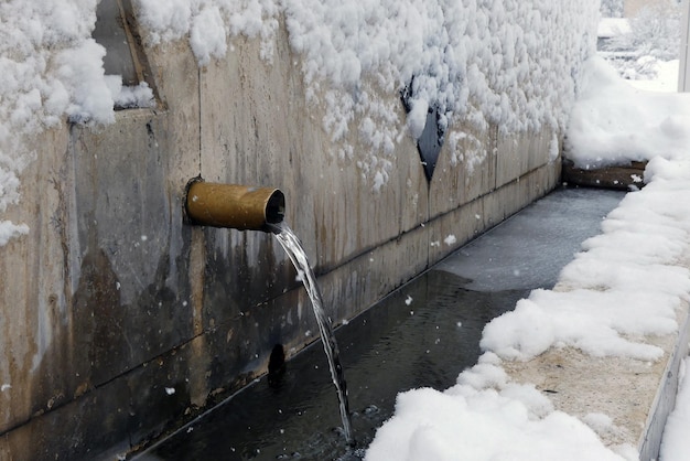 Una fontana d'inverno una fontana nel paesaggio innevato una fontana che ha iniziato a gelare