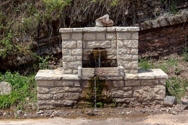 Una fonte di pietra closeup con acqua fredda e limpida in montagna in una soleggiata giornata estiva regione Tzoumerka Grecia montagne Pindos