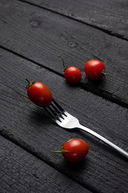 Una forchetta con sopra un pomodoro su un tavolo nero