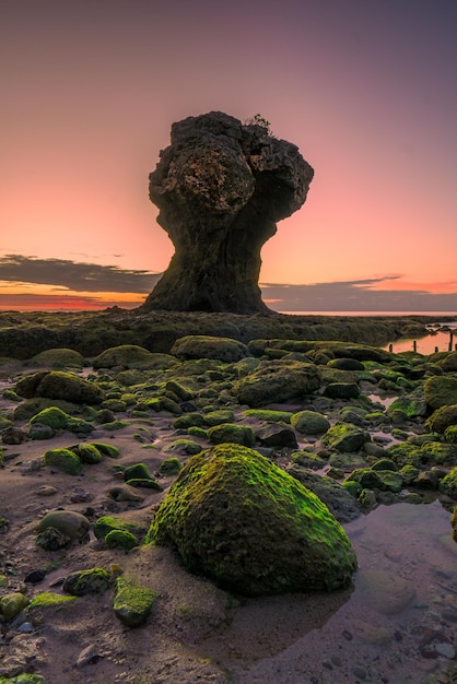 Una formazione rocciosa sulla spiaggia al tramonto