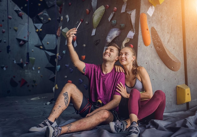 Una forte coppia di arrampicatori contro una parete artificiale con appigli e corde colorate