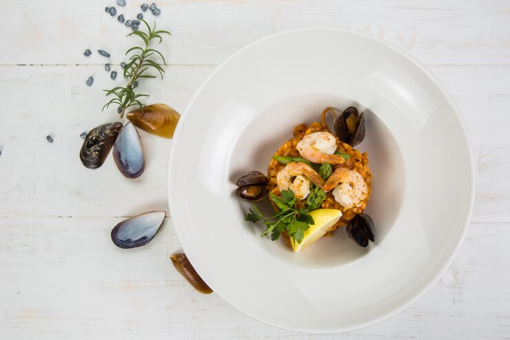 Una foto aerea di un risotto ai frutti di mare su trame di alzavola, con una forchetta e un cucchiaio, un bicchiere di vino bianco e un posto per il testo