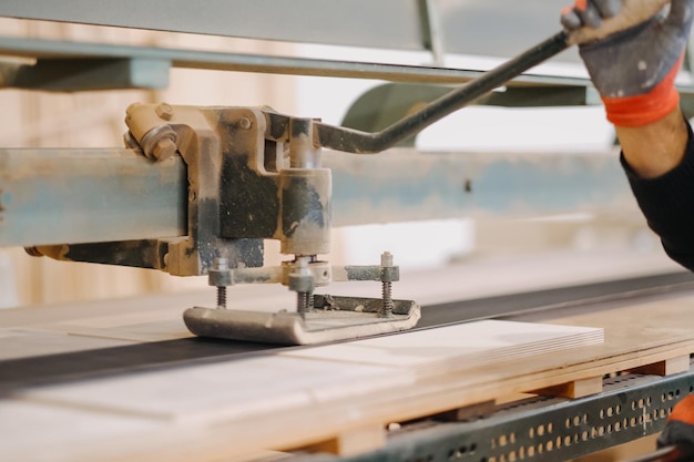 Una foto da vicino di una persona che opera una macchina industriale per tagliare il legno