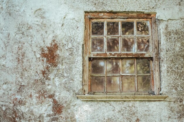 Una foto da vicino di una vecchia finestra di legno su un edificio in pietra