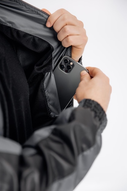 Una foto da vicino su uno sfondo bianco di un uomo che tira fuori un gadget dalla tasca interna della giacca