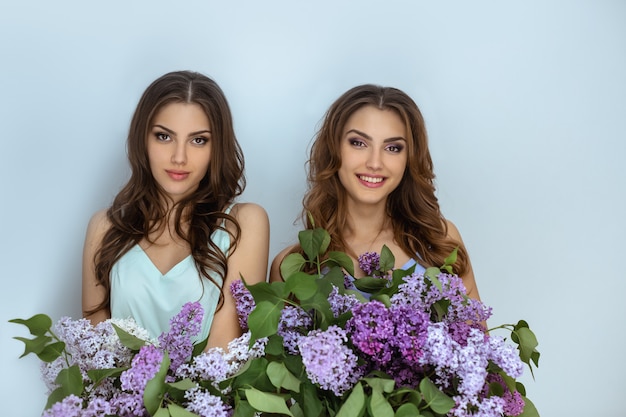 Una foto del ritratto di modo dello studio di due donne dei gemelli con un mazzo dei fiori della molla