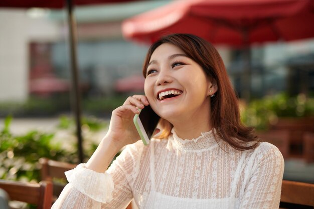 Una foto di una donna asiatica che parla al telefono