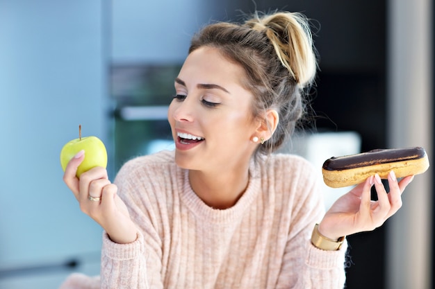 Una foto di una donna che sceglie tra mela ed eclair