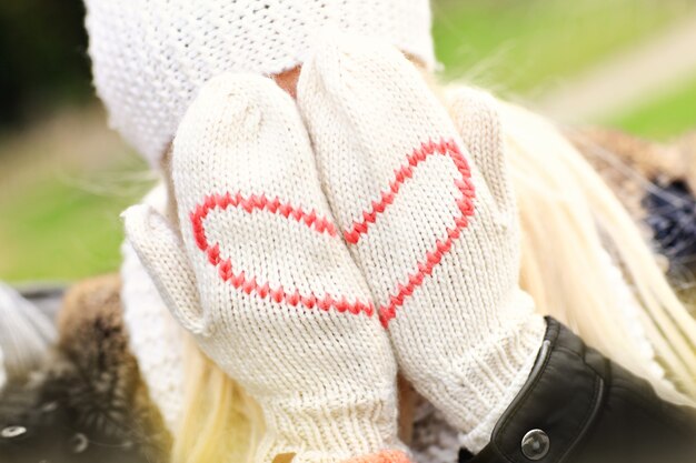 Una foto di una donna che si copre il viso con i guanti invernali