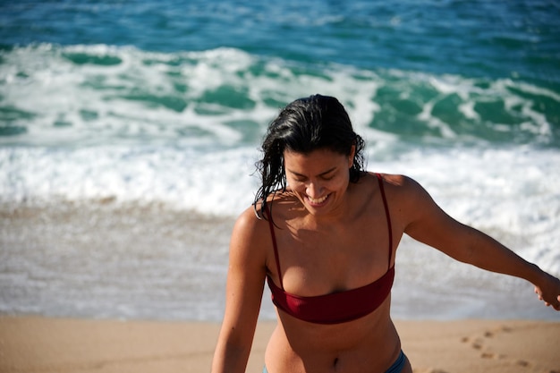 Una foto di una donna sorridente che indossa un costume da bagno bikini in spiaggia