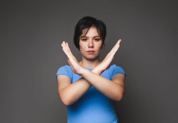 Una foto di una giovane donna piuttosto seria con le braccia incrociate mostra il divieto di sosta proibito evidenziato su uno sfondo grigio