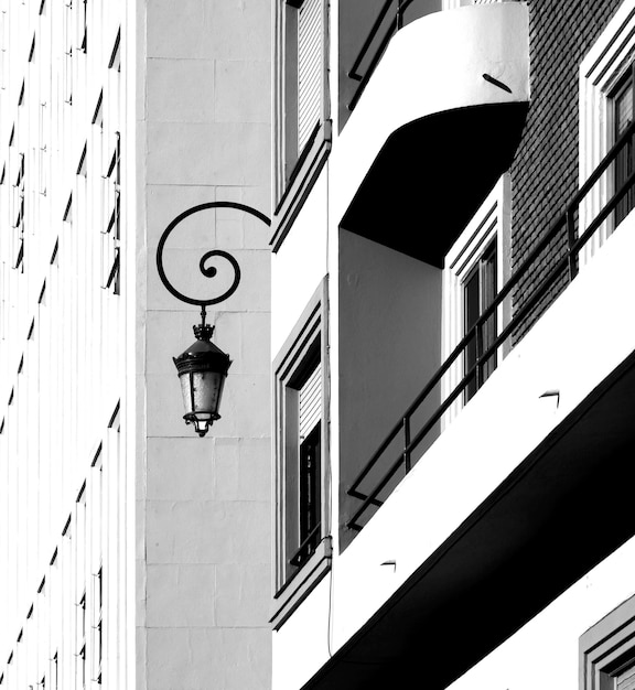 Una foto in bianco e nero di un edificio con una lampada appesa lateralmente.