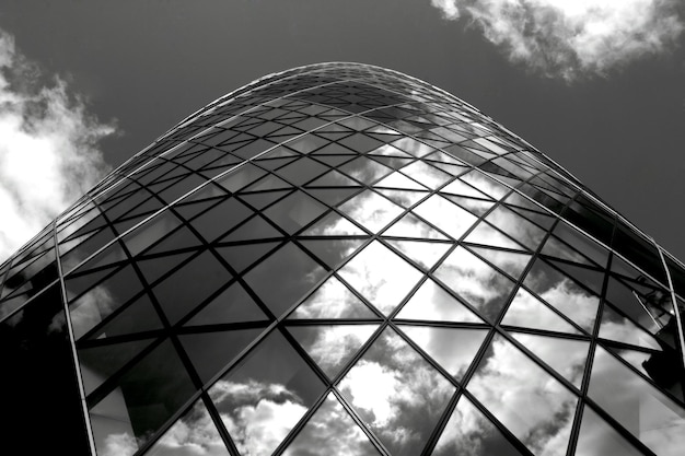 Una foto in bianco e nero di un edificio in vetro con il cielo sullo sfondo.