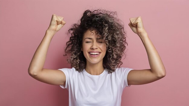 Una foto isolata di una bella donna di successo con i capelli ricci che alza i pugni chiusi per festeggiare il triu.