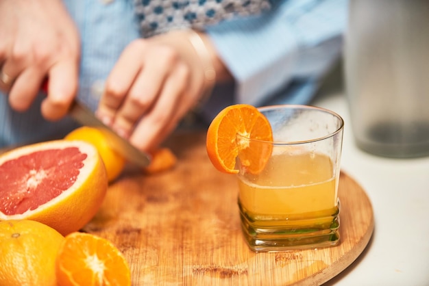 Una foto ravvicinata della mano di una donna che taglia e prepara i frutti per fare un frullato sano Il concetto di uno stile di vita sano