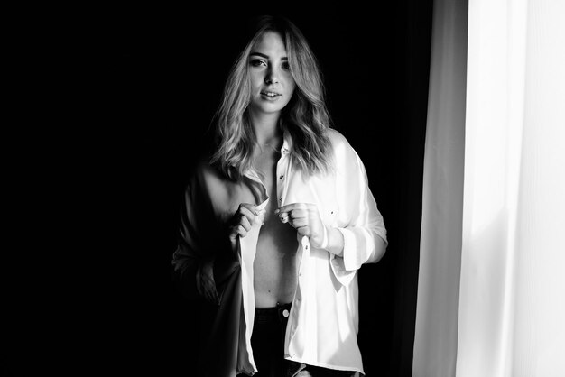 Una fotografia in bianco e nero di una ragazza che si abbottona la camicia Concetto di buongiorno