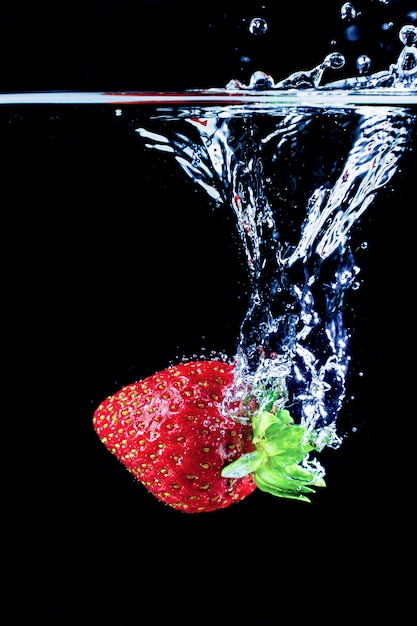 Una fragola che spruzza nell'acqua sul nero