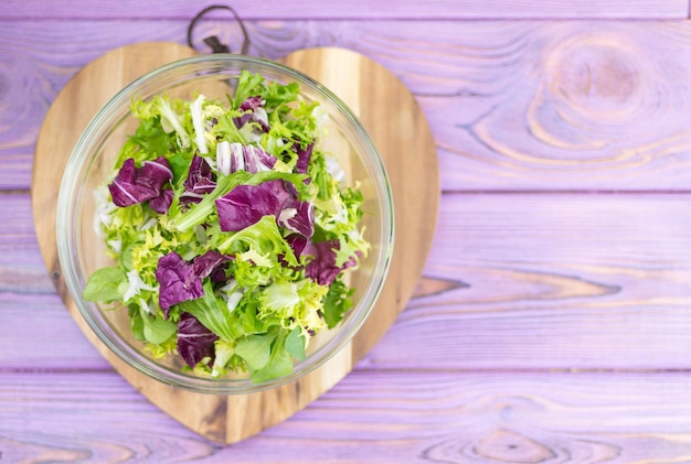 Una fresca insalata di verdure su uno sfondo di legno a forma di cuore Cibo vegetariano Dieta
