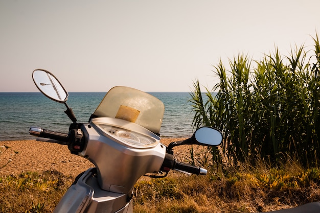 Una generica bici da scooter d&#39;argento è parcheggiata in riva al mare.