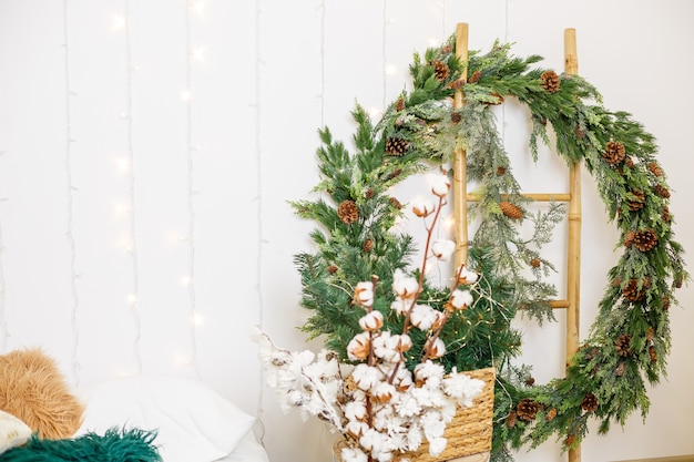 Una ghirlanda di Capodanno dai rami di un albero di Natale è appesa al muro. Decorazioni in casa per il nuovo anno. Arredare la stanza per le vacanze di Capodanno