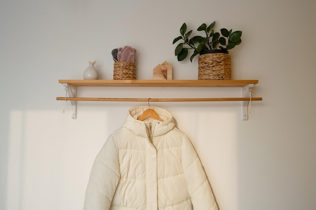 Una giacca bianca è appesa all'interno di una stanza con uno spazio libero su una mensola di legno