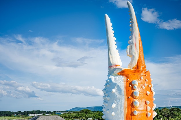 Una gigantesca scultura di mostro arancione con un cielo blu sullo sfondo.