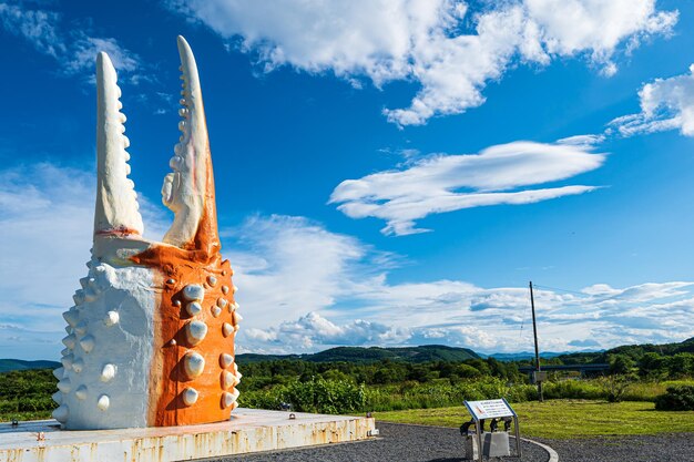 Una gigantesca statua di dinosauro si trova di fronte a una collina e montagne.