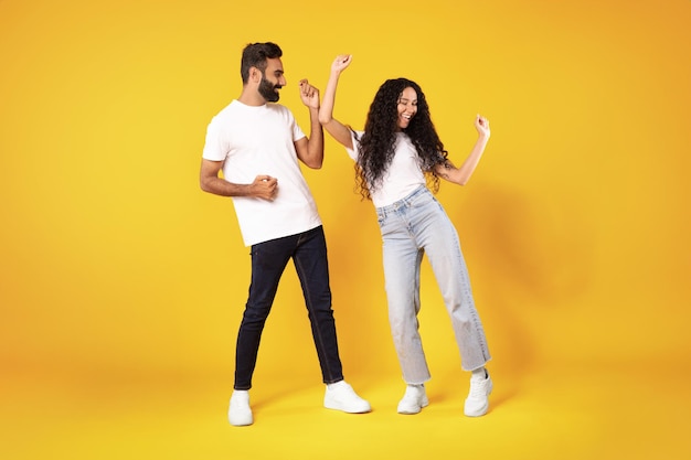 Una gioiosa coppia araba che danza per festeggiare la buona notizia su uno sfondo giallo